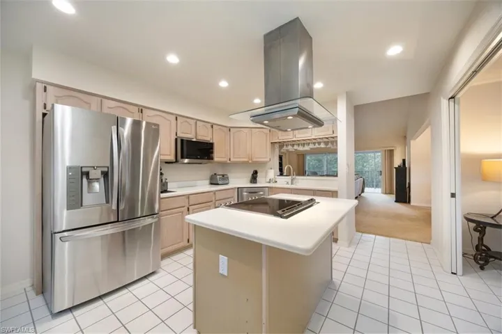 Kitchen with light brown cabinets, stainless steel appliances, light tile patterned floors, island exhaust hood, and light countertops