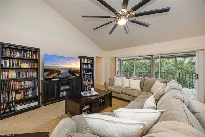 Carpeted living room with a healthy amount of sunlight, ceiling fan, and high vaulted ceiling