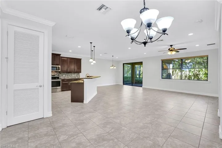 Kitchen featuring pendant lighting, backsplash, ornamental molding, dark brown cabinetry, and stainless steel appliances