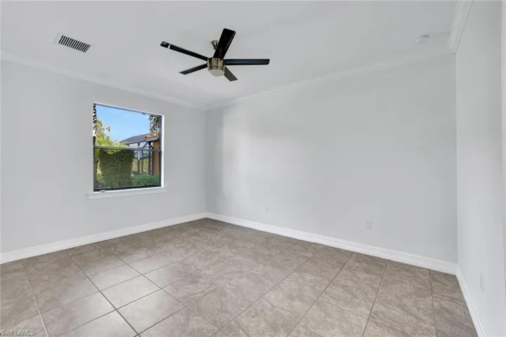 Tiled empty room with crown molding and ceiling fan