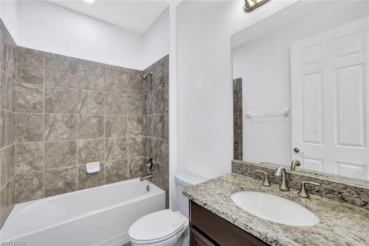 Full bathroom with vanity, tiled shower / bath combo, and toilet