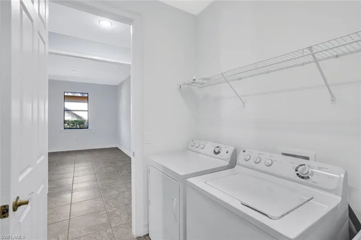 Laundry area with washing machine and clothes dryer and light tile patterned flooring