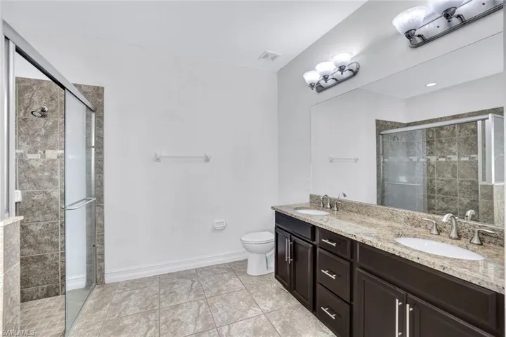 Bathroom with vanity, an enclosed shower, tile patterned floors, and toilet