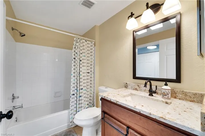 Bathroom with shower / tub combo, vanity, and a textured wall