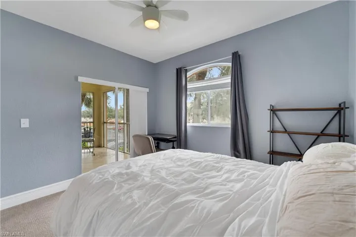 Bedroom with access to exterior, a textured wall, ceiling fan, and light colored carpet