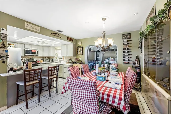 Tiled dining space featuring ceiling fan with notable chandelier