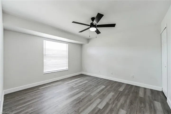 Empty room with dark hardwood / wood-style floors and ceiling fan
