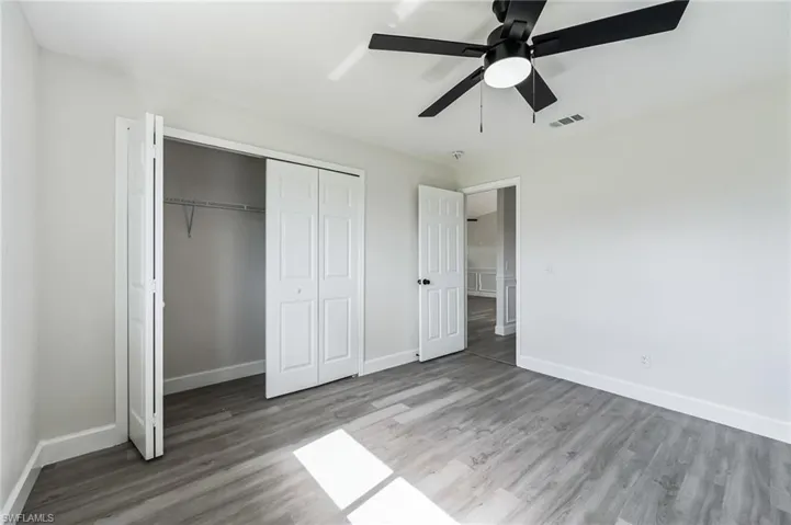 Unfurnished bedroom with ceiling fan, a closet, and wood-type flooring
