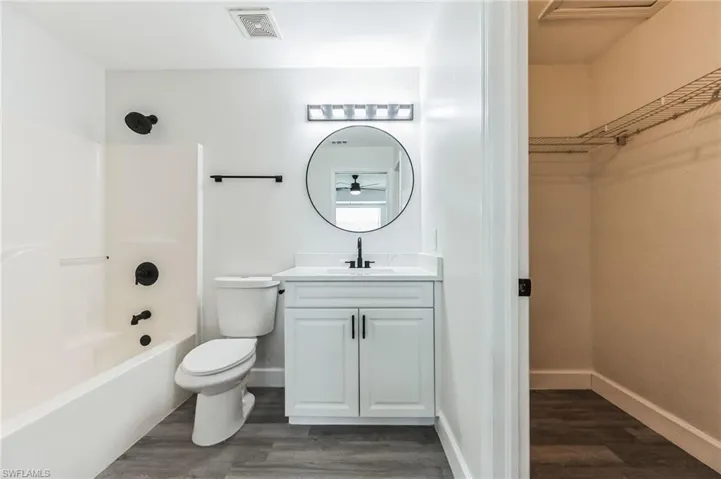 Full bathroom with bathtub / shower combination, hardwood / wood-style floors, toilet, and vanity