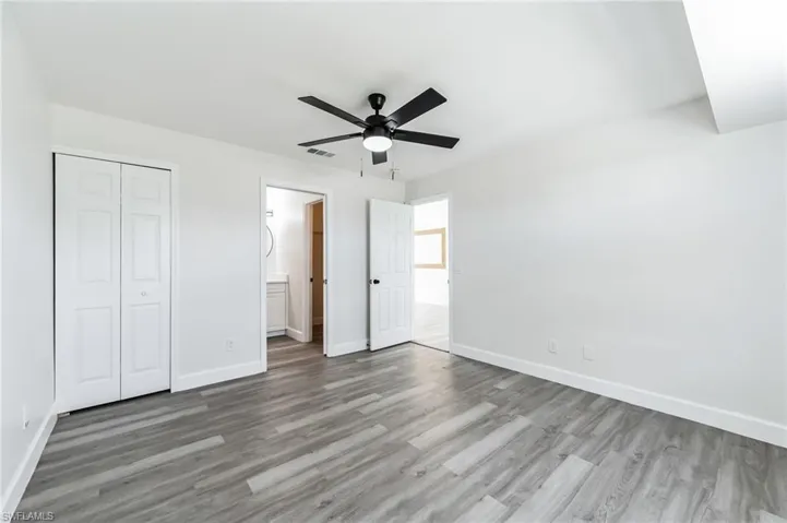 Unfurnished bedroom with ceiling fan, a closet, hardwood / wood-style floors, and ensuite bathroom