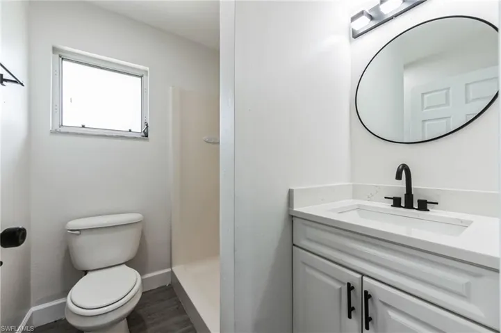 Bathroom with walk in shower, vanity, toilet, and hardwood / wood-style floors