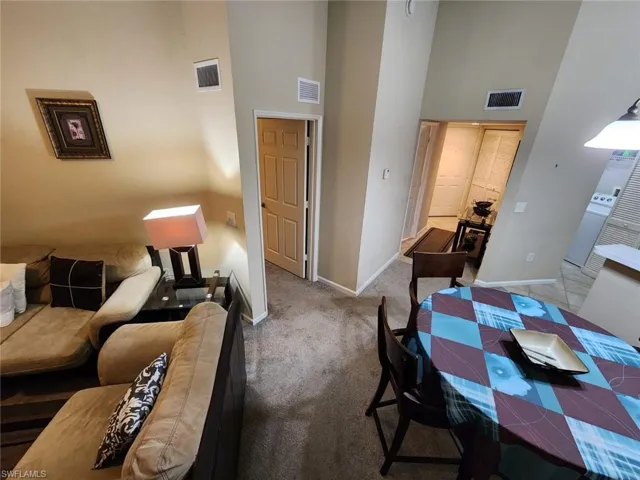 Carpeted dining room featuring a high ceiling and baseboards