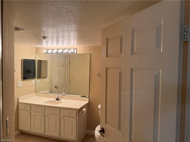 Bathroom with vanity, a textured ceiling, and light tile patterned floors