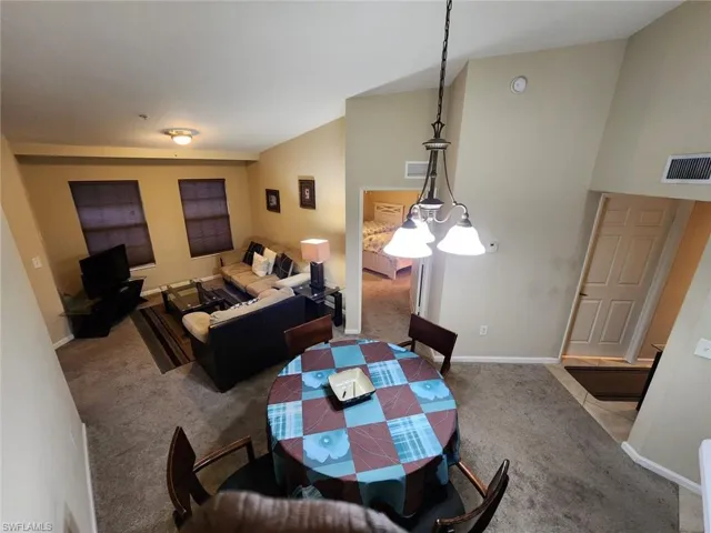 Dining area with light carpet and vaulted ceiling
