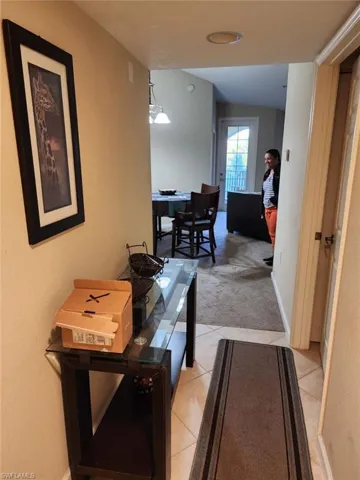 Hallway with light carpet and light tile patterned floors