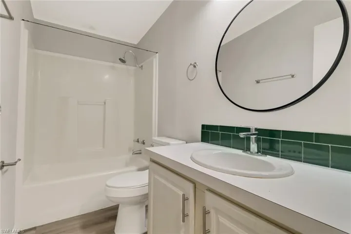 Full bathroom featuring hardwood / wood-style floors, vanity, toilet, and shower / tub combination