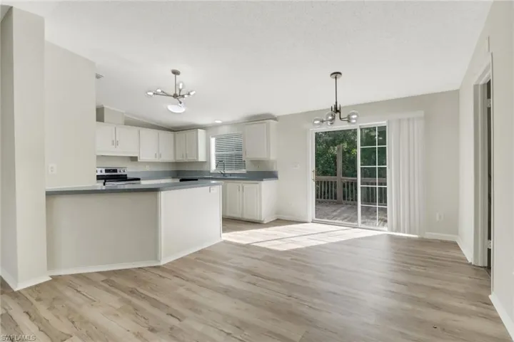 Kitchen with electric range, decorative light fixtures, white cabinetry, and a chandelier