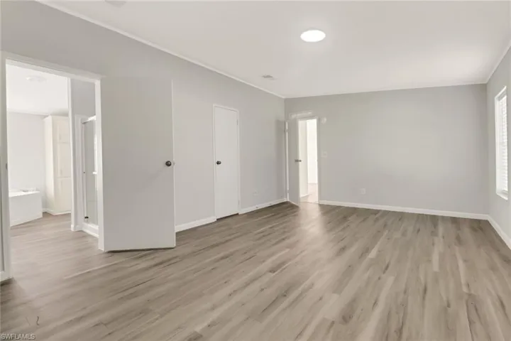 Unfurnished bedroom featuring connected bathroom and light hardwood / wood-style floors