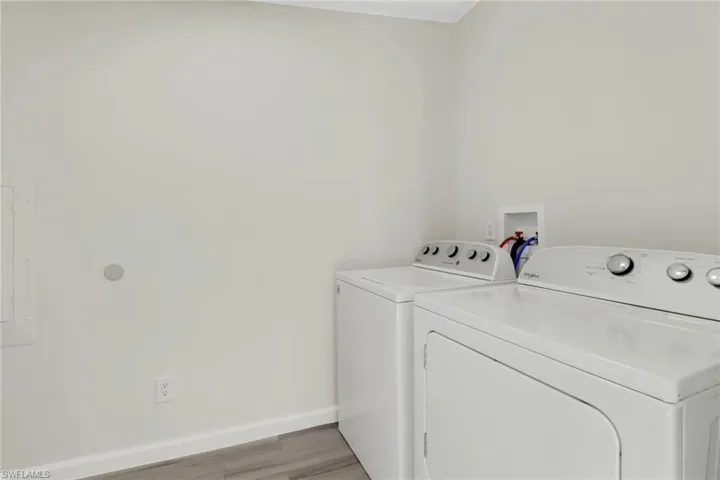 Laundry area featuring separate washer and dryer, electric panel, and light hardwood / wood-style floors
