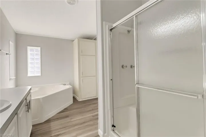 Bathroom with shower with separate bathtub, vanity, and hardwood / wood-style flooring
