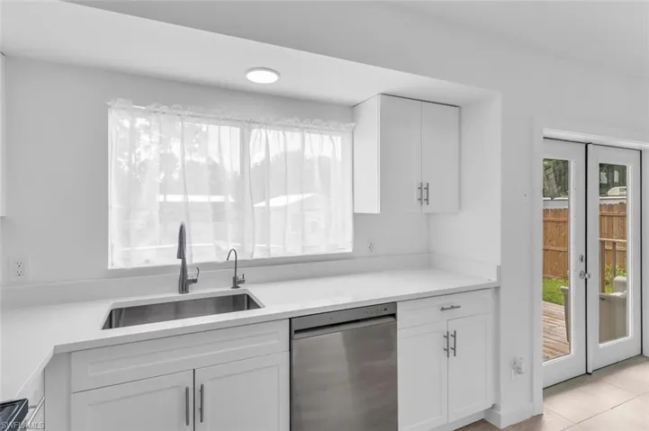 Kitchen with white cabinets, dishwasher, sink, and plenty of natural light
