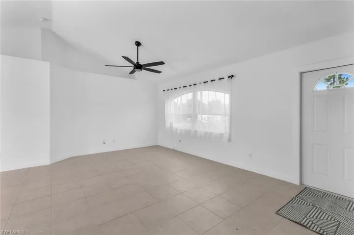 Tiled foyer entrance featuring lofted ceiling and ceiling fan