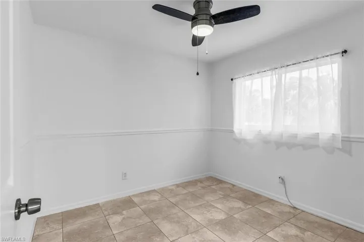 Empty room with ceiling fan and light tile patterned floors