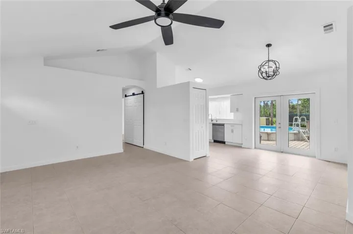 Unfurnished living room with ceiling fan, light tile patterned flooring, vaulted ceiling, and french doors