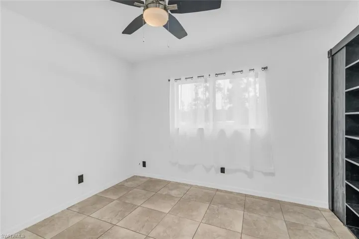 Tiled spare room featuring ceiling fan