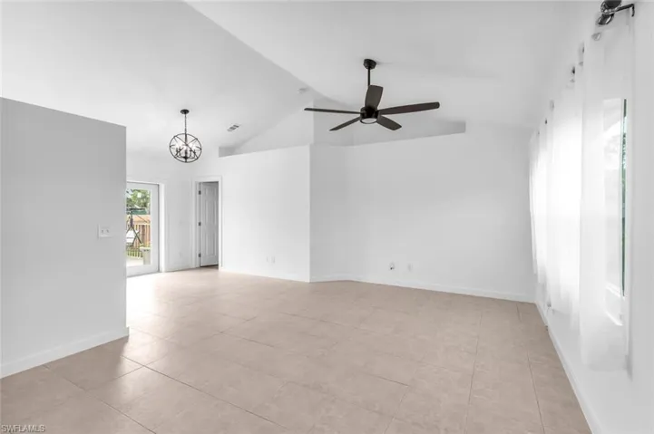 Spare room with high vaulted ceiling, ceiling fan with notable chandelier, and light tile patterned floors