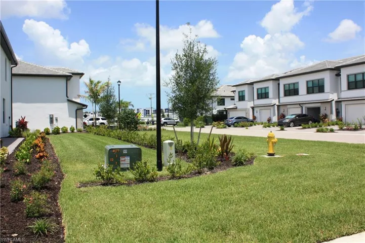 Manicured lawn with mature landscaping and clear sky