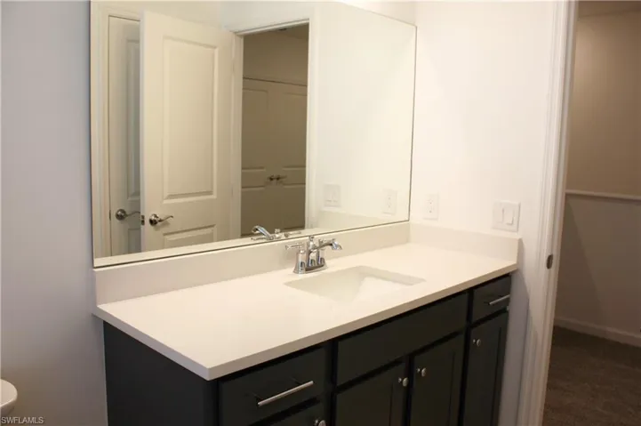 Vanity featuring a light-colored countertop, integrated sink, and dark cabinetry with brushed nickel hardware