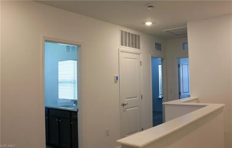 Upper-level hallway with white painted walls and recessed lighting