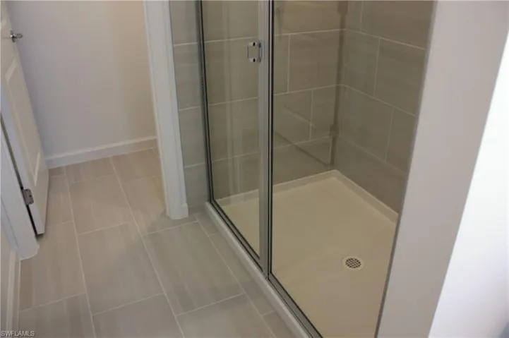 Shower enclosure with clear glass doors and light gray tile surround