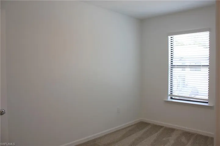 Light-colored walls complement the window with horizontal blinds, offering privacy