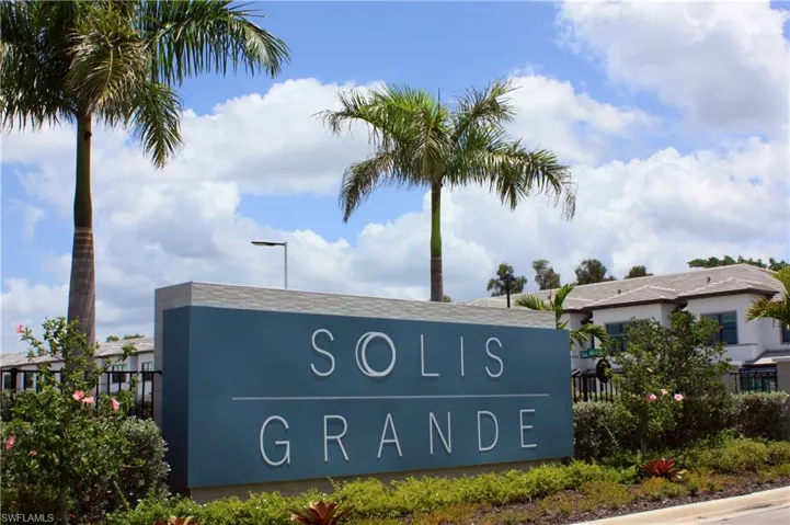 Entrance sign featuring "SOLIS GRANDE" lettering, surrounded by lush landscaping and established palm trees