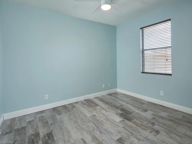 Guest bedroom with updated flooring and soft natural light.