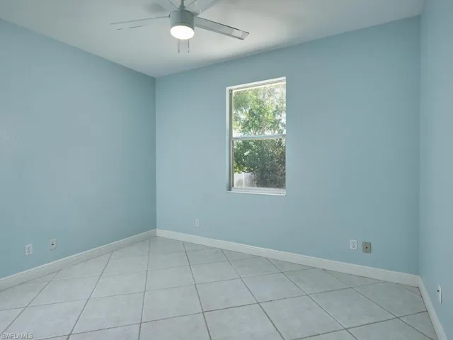 Second guest bedroom with neutral tones and backyard views.