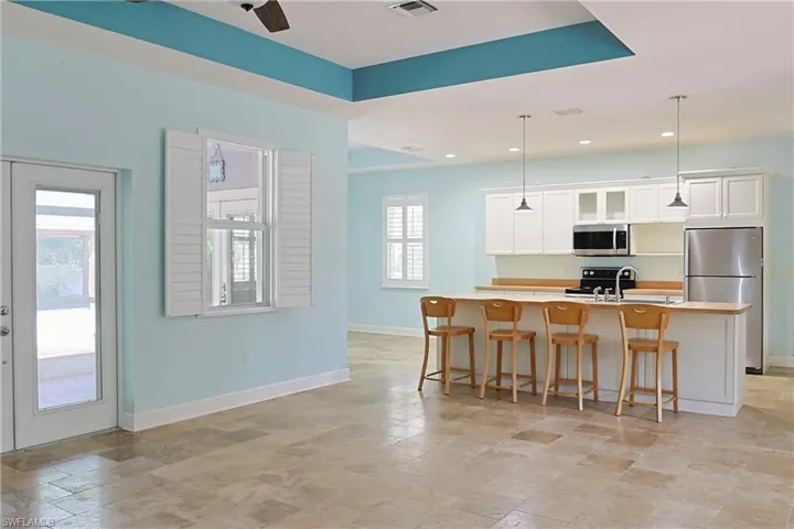 Kitchen featuring a breakfast bar area, stainless steel appliances, white cabinets, light countertops, and stone finish flooring