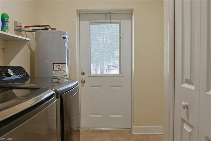 Laundry area featuring electric water heater and separate washer and dryer