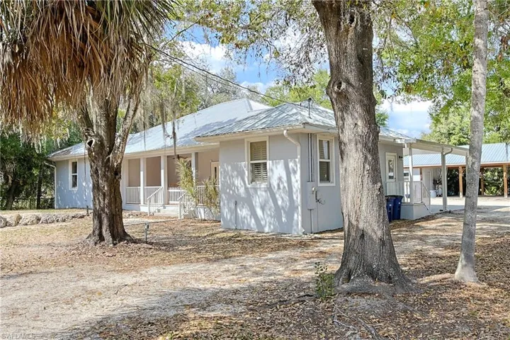 Single story home with a metal roof, a carport, and stucco siding
