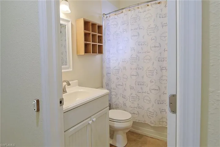 Bathroom featuring vanity, a textured wall, and shower / bath combination with curtain