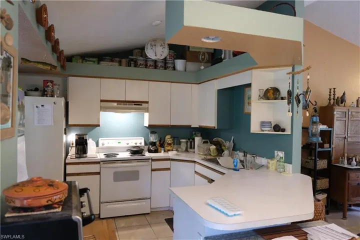Kitchen with white cabinetry, a built-in oven range, and a breakfast bar