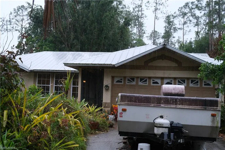Single-story residence featuring a metal roof, attached garage with decorative transom windows, and a screened entry