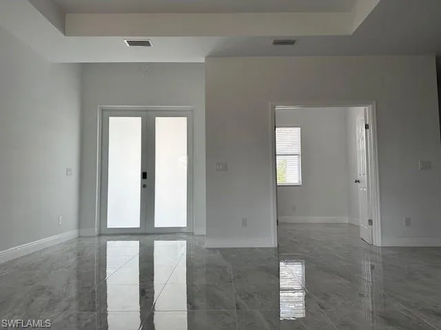 Spare room featuring a tray ceiling and french doors