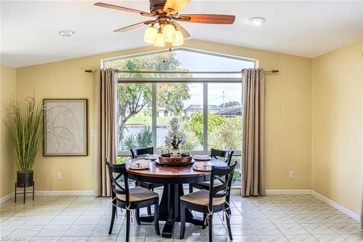 Vaulted ceiling featuring a central multi-light fan, expansive trapezoidal window with ocean views, and tile flooring