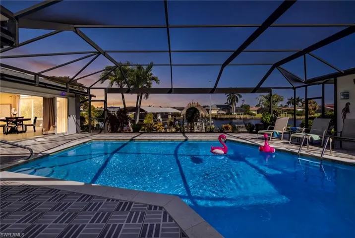 Screened-in lanai featuring an in-ground swimming pool, decorative tile pool deck, and water frontage