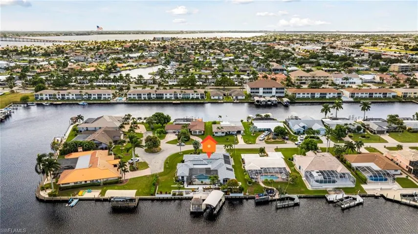 Waterfront residence featuring a private boat dock, covered boat lift, screened pool enclosure, and tile roofing