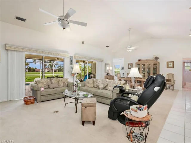 Spacious living area featuring vaulted ceilings, ceiling fans, and neutral carpeting