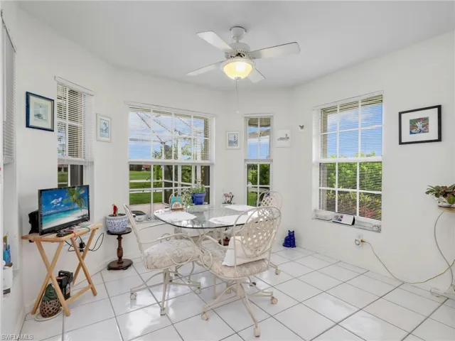 Bright interior space featuring multiple windows, a ceiling fan with integrated lighting, and white tile flooring